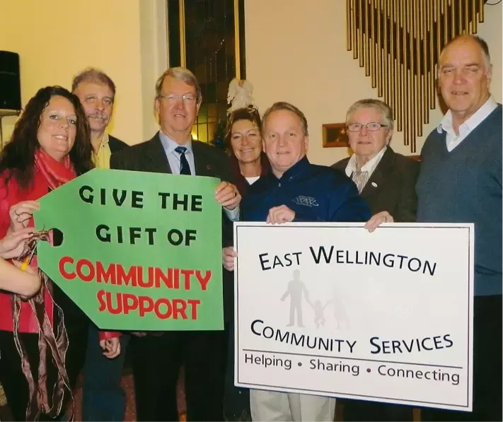 group of people with sign saying give the gift of community support